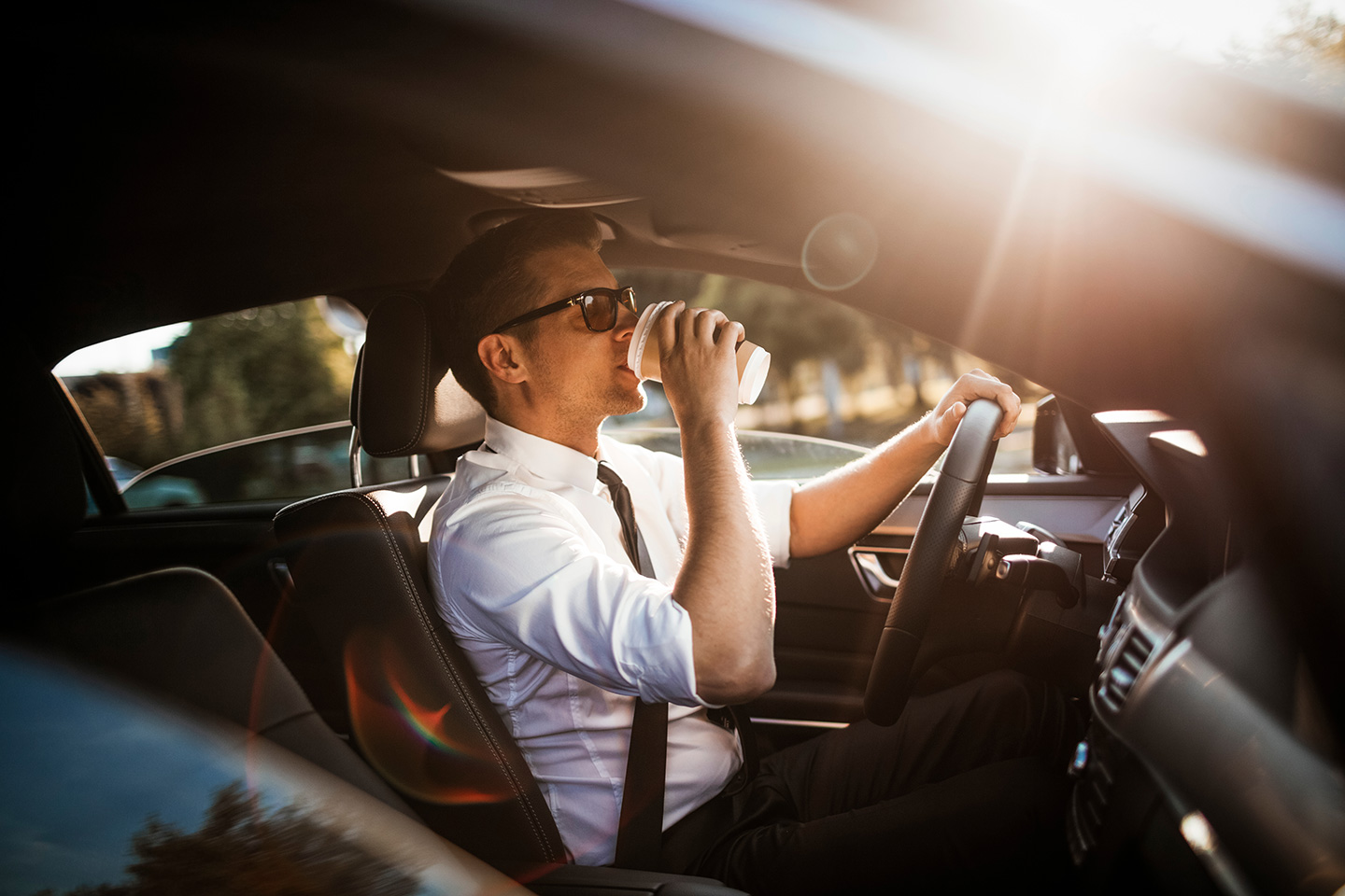communter drinking coffee in car in traffic